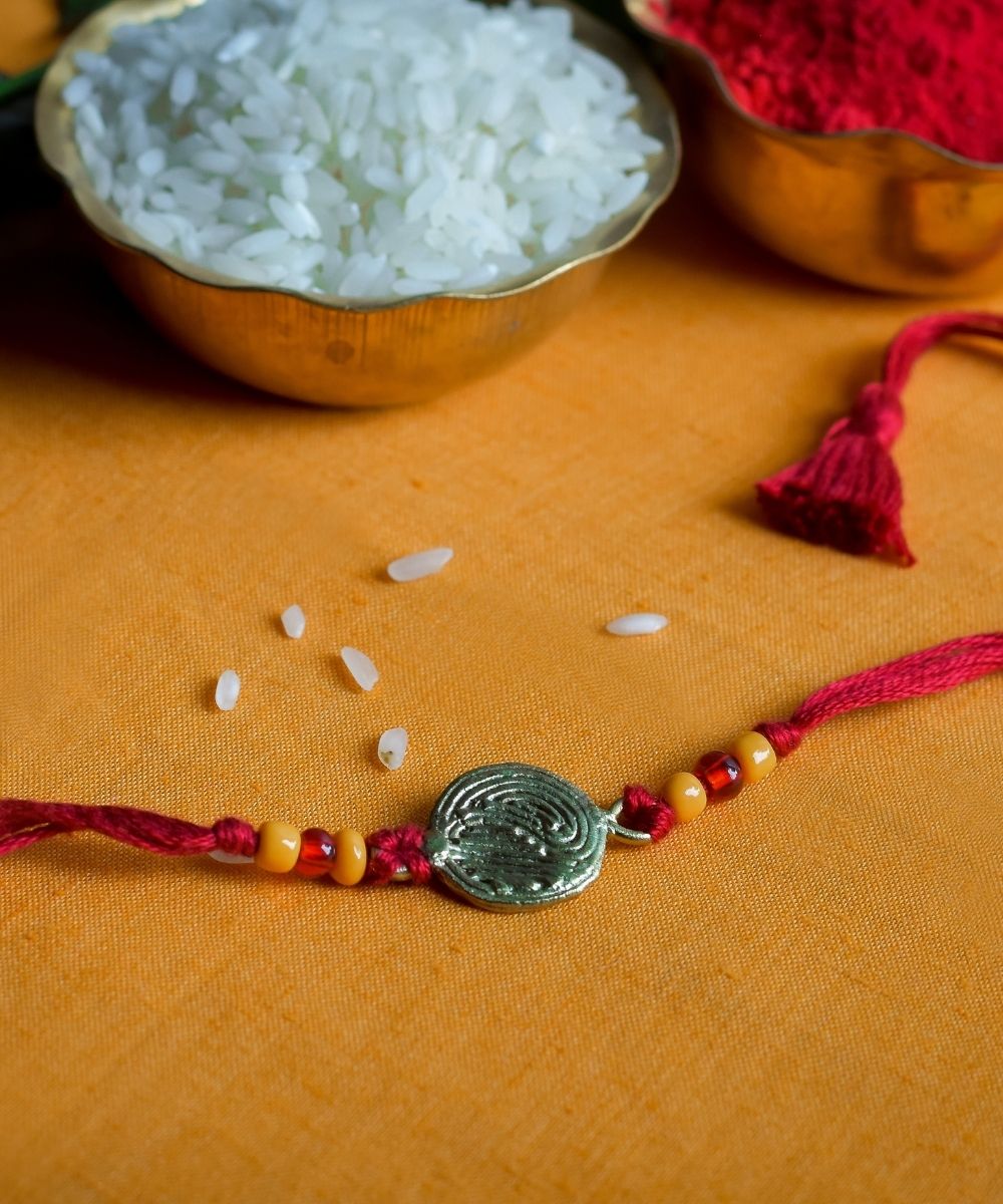 Hand crafted dhokra rakhi with red mercerised cotton thread